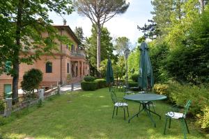una mesa y sillas con sombrillas en un patio en Villa delle Rose - Hotel Paradiso, en Amandola