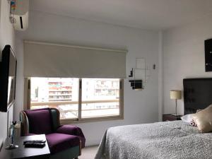 een slaapkamer met een bed, een stoel en een raam bij Rent Apart Caballito in Buenos Aires