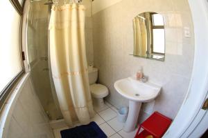 y baño con cortina de ducha y lavamanos. en Hostal del Cerro, en Santiago