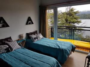 two beds in a room with a large window at Albanta casa con costa en Bariloche in San Carlos de Bariloche