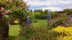 a garden with colourful flowers and trees in the background at Shurinji in Whanganui