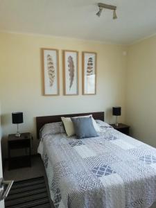 1 dormitorio con 1 cama con 3 cuadros en la pared en Apartamento Portal Pacífico, en La Serena