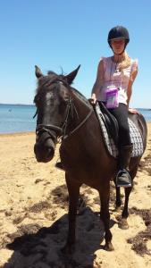 a woman is riding a horse on the beach at Bass Coast Country Cottages in Bass