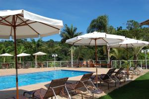 a group of chairs and umbrellas next to a pool at Pousada Nefelibatas in Águas de Lindoia