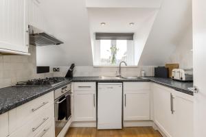 cocina con armarios blancos, fregadero y ventana en Gorgeous Apartment in the centre of Winchester, en Winchester