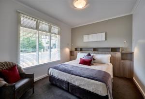 a bedroom with a large bed and a chair at Mews Cottages in Gisborne