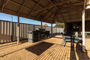 um pátio com comodidades para churrascos, uma mesa e cadeiras em Sails Geraldton Accommodation em Geraldton