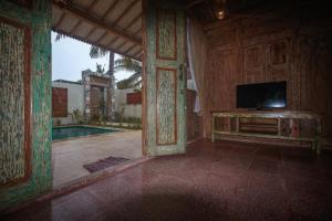 a living room with a tv and a pool at Villa Coco Republic in Gili Air