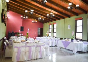 uma sala com mesas e cadeiras com toalhas de mesa brancas em Hotel Las Candelas de Huamantla em Huamantla