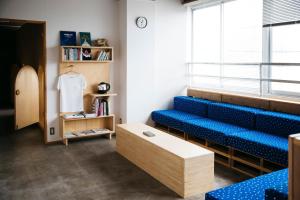 een wachtkamer met blauwe stoelen en een tafel bij Iwashi Building Hostel in Akune