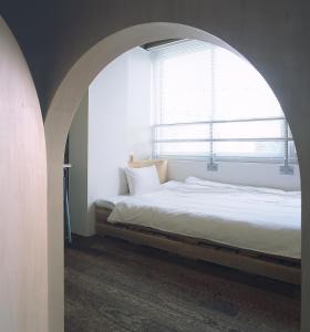 een slaapkamer met een boog, een bed en een raam bij Iwashi Building Hostel in Akune
