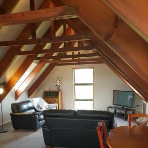 a living room with a black leather couch and a tv at Accommodation at Lakeside in Oamaru