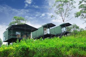 dos casas verdes con techos negros en la cima de un campo en Box on clouds en Ella