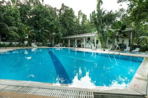 a large blue swimming pool with trees in the background at Ras Resort By Treat Silvassa in Silvassa