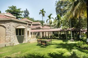 a house with a yard with chairs and a table at Ras by Treat Resorts, Silvassa - in Silvassa