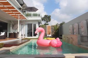 un flamingo rose gonflable dans une piscine dans l'établissement Villa Arusha Jogja, à Sleman