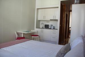 a bedroom with a bed and a small kitchen at Loulé Estúdios in Porto