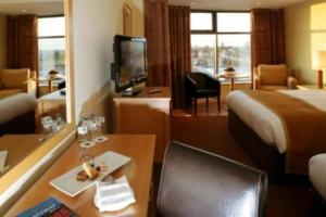 Mullingar Park Hotel في مولينجار: غرفة في الفندق مع مكتب وغرفة مع سرير وطاولة طعام
