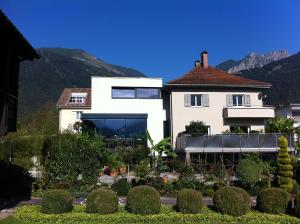 a white house with a garden and mountains in the background at Ferienwohnung iq-Sports in Bludenz