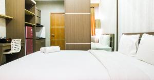 a bedroom with a large white bed and a desk at New Studio The Oasis Apartment By Travelio in Cikarang