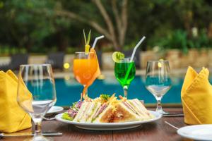 a table with a plate of food and glasses of juice at Liyya Water Villas in Dambulla