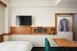 a bedroom with a television and a bed at Nishitetsu Inn Nihonbashi in Tokyo