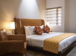 a bedroom with a bed with a chair and a window at The Mayberry -A Bergamont Group of Hotels in Tiruppūr