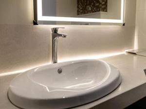 a white bathroom sink with a faucet on a counter at The Mayberry -A Bergamont Group of Hotels in Tiruppūr
