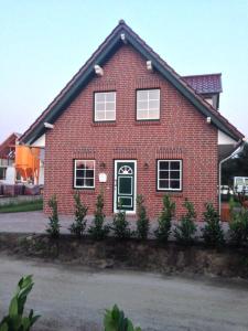 a red brick house with a green door at Ferienhaus Pusteblume in Garrel