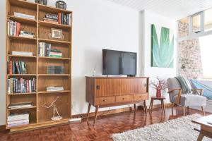 uma sala de estar com televisão num centro de entretenimento em madeira em House Sandrock Muckleneuk Selfcatering apartment em Pretoria