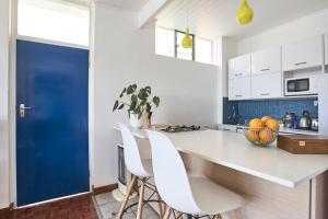 uma cozinha com balcões brancos e uma porta azul em House Sandrock Muckleneuk Selfcatering apartment em Pretoria