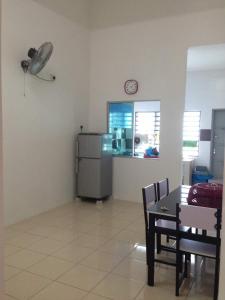una cucina con frigorifero, tavolo e sedie di NUHA HOMESTAY a Seri Iskandar