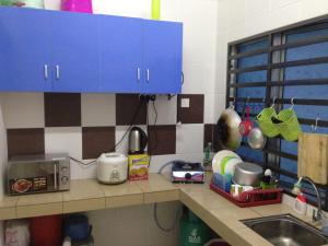 encimera de cocina con fregadero y armarios azules en NUHA HOMESTAY en Seri Iskandar