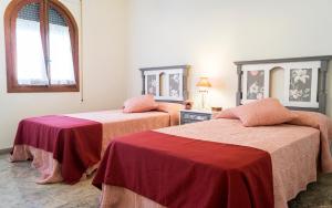 Cette chambre comprend 2 lits avec des draps rouges et roses. dans l'établissement Capitulares, à Cordoue