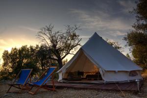a white tent with two blue chairs and the sunset at Shauri Glamping in Noto +19 photos
