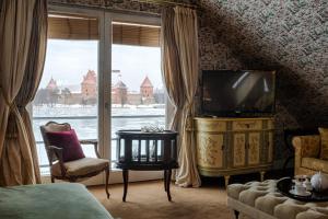 a bedroom with a television and a large window at Apvalaus stalo klubas in Trakai