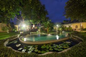 a swimming pool in a garden at night at Villa Costa Plenty in Sanur