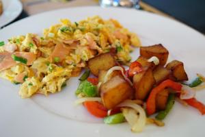 a plate of food with scrambled eggs and potatoes at Metro Apartments in Pattaya
