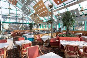 Royal Garden في أسّاغو: مطعم بطاولات وكراسي في غرفة بها نوافذ