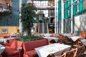 restauracja z białymi stołami i czerwonymi krzesłami w obiekcie Royal Garden Assago Milano w mieście Assago