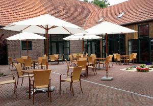 an outdoor patio with tables and chairs and umbrellas at Lindenhof Gästehaus & Hofcafe in Kranenburg