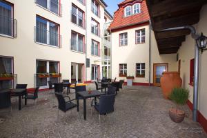 een binnenplaats met tafels, stoelen en gebouwen bij Garni-Hotel zum alten Ratskeller in Vetschau