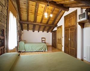 Un dormitorio con una cama verde y techos de madera. en Apartamentos Casa Buisan, en Broto