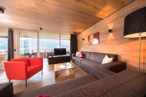 a living room with a couch and a red chair at Chalet Bergblick in Bramberg am Wildkogel