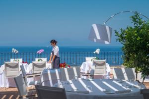 a woman standing in front of a table and chairs at Relais Maresca Luxury Small Hotel & Terrace Restaurant in Capri