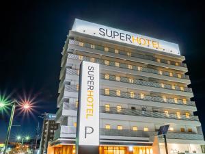 un edificio con un super cartello di hotel di fronte di Super Hotel Yamagata Sakurambo-Higashine Station Front a Higashine