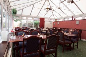 un comedor con mesas, sillas y ventanas en Roselawn Hotel, en Reading
