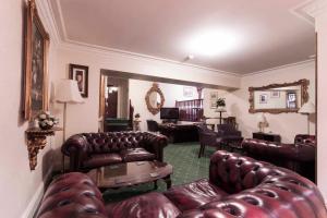 a living room with leather couches and a table at Roselawn Hotel in Reading