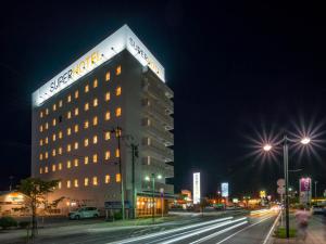 a lit up building on a city street at night at Super Hotel Yamagata Sakurambo-Higashine Station Front in Higashine