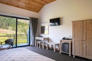 a bedroom with a bed and a balcony with a television at Houw Hoek Hotel in Botrivier